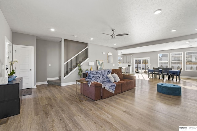 living room with a textured ceiling, light hardwood / wood-style flooring, and ceiling fan