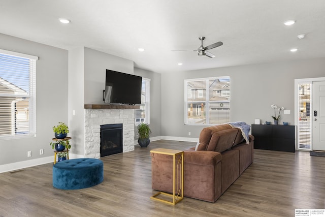 living room featuring a stone fireplace, ceiling fan, and wood-type flooring