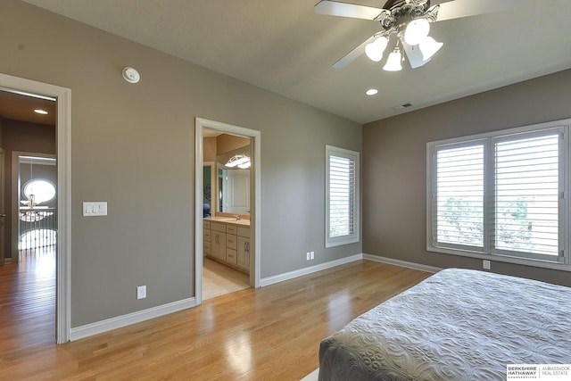 bedroom featuring light hardwood / wood-style flooring, ensuite bath, ceiling fan, and sink