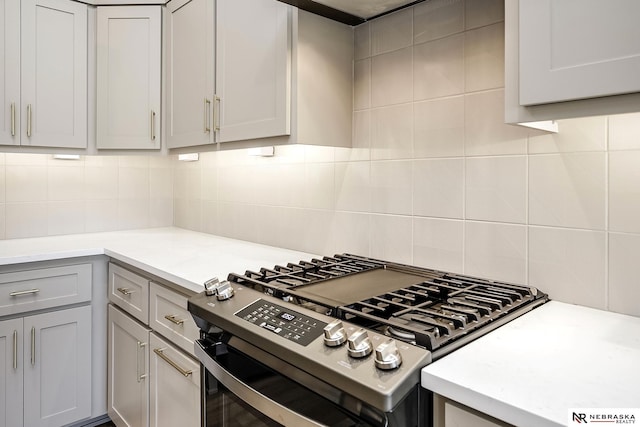 kitchen featuring tasteful backsplash, light stone counters, gas range, and gray cabinets