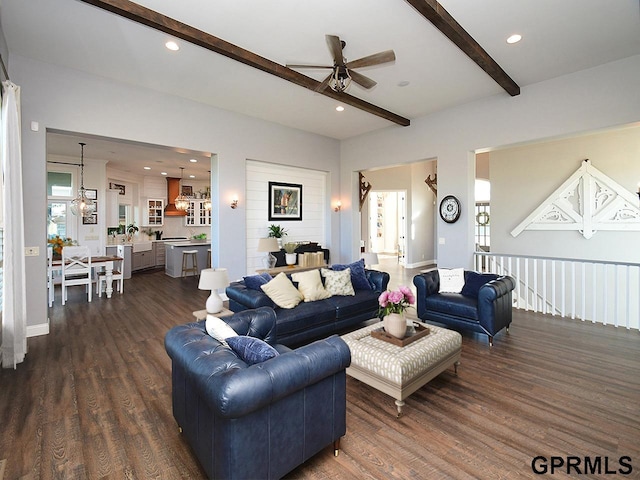 living room with dark hardwood / wood-style flooring, beamed ceiling, and ceiling fan with notable chandelier