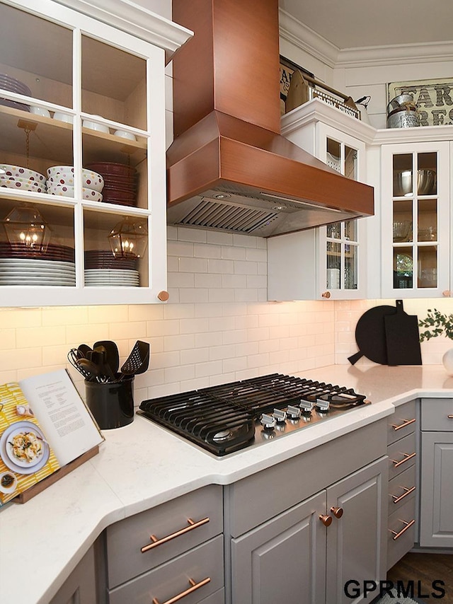 kitchen featuring stainless steel gas cooktop, tasteful backsplash, premium range hood, crown molding, and gray cabinets