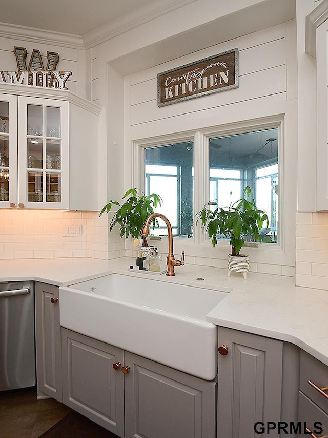 kitchen featuring gray cabinetry, sink, light stone counters, stainless steel dishwasher, and ornamental molding