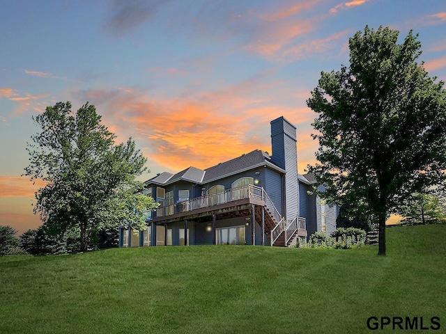 back house at dusk featuring a lawn