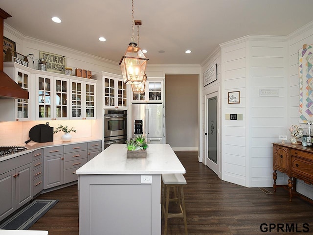 kitchen with gray cabinets, appliances with stainless steel finishes, decorative light fixtures, a kitchen island, and white cabinetry