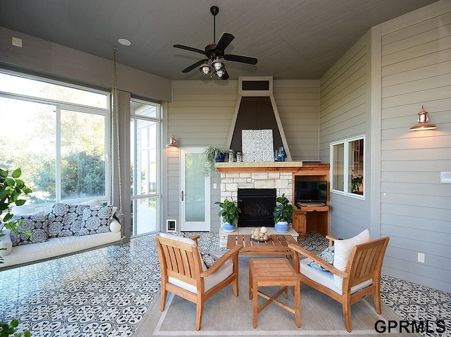 sunroom / solarium featuring a stone fireplace and ceiling fan