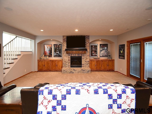 living room with a fireplace, light carpet, and a textured ceiling