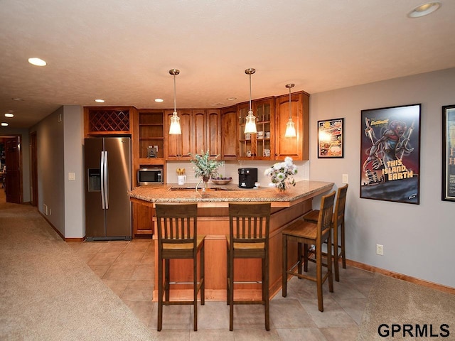 kitchen with a kitchen bar, kitchen peninsula, stainless steel appliances, and decorative light fixtures