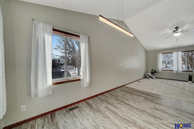 spare room with ceiling fan, vaulted ceiling, a healthy amount of sunlight, and hardwood / wood-style floors