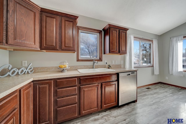 kitchen with sink, light wood-type flooring, stainless steel dishwasher, and vaulted ceiling