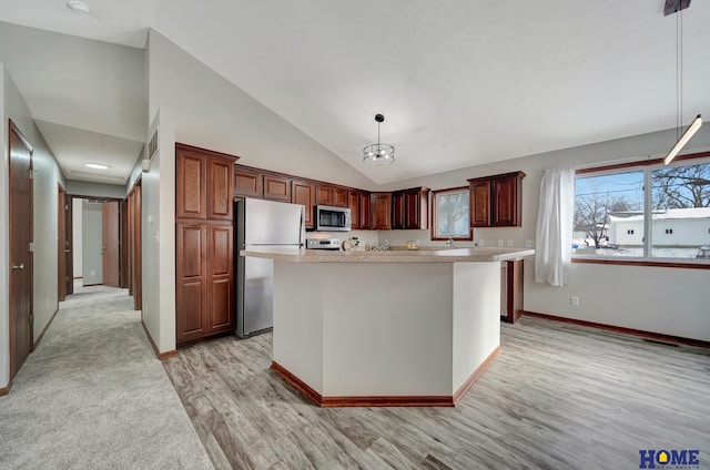 kitchen with stainless steel appliances, decorative light fixtures, a center island, light hardwood / wood-style floors, and high vaulted ceiling