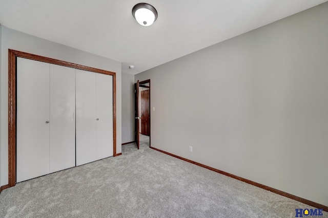 unfurnished bedroom with light colored carpet and a closet