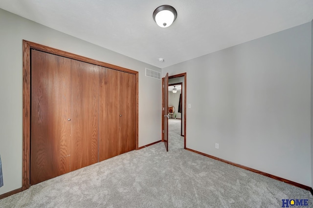 unfurnished bedroom featuring light colored carpet and a closet