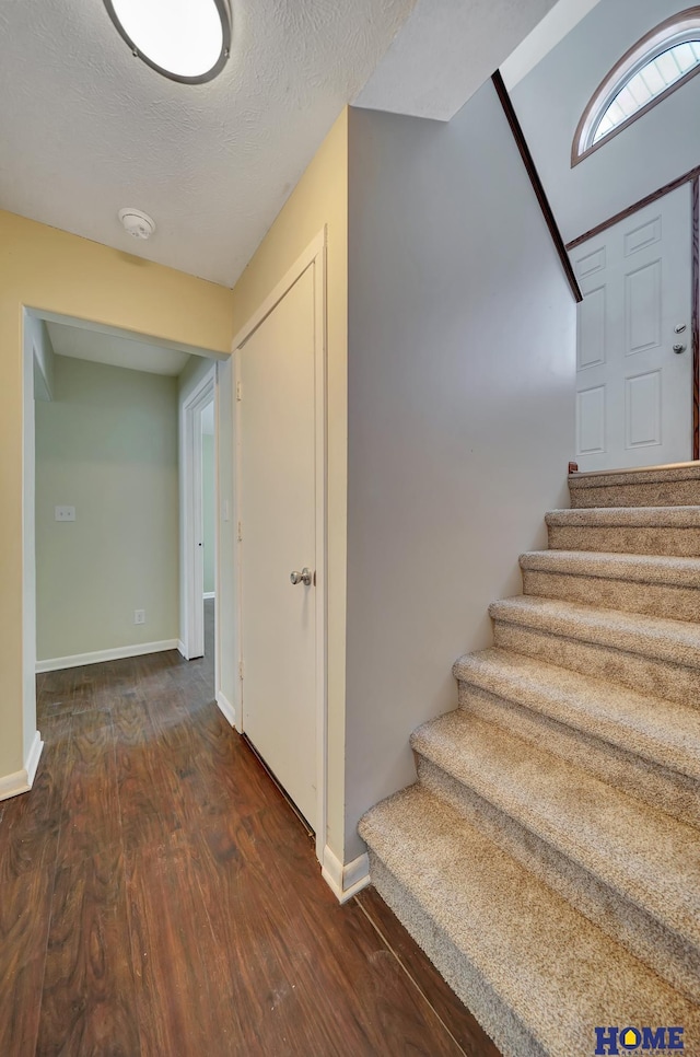 staircase featuring a textured ceiling and hardwood / wood-style floors