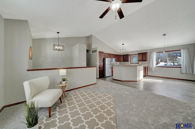 living room with lofted ceiling, ceiling fan with notable chandelier, and light colored carpet