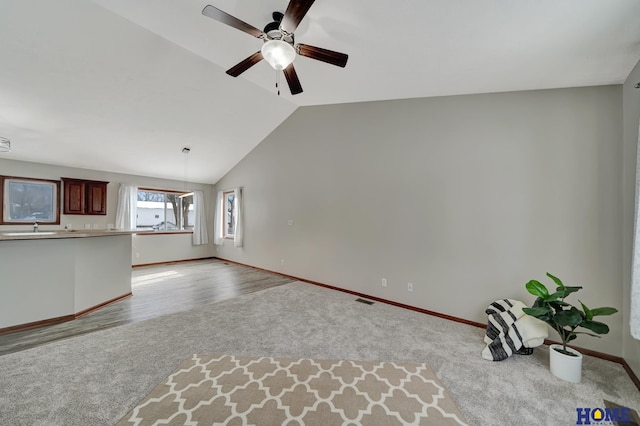 unfurnished living room with lofted ceiling, light colored carpet, and ceiling fan