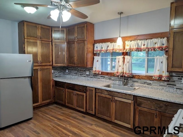 kitchen with light stone countertops, sink, decorative light fixtures, white fridge, and dark hardwood / wood-style floors