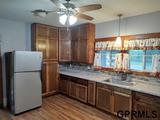 kitchen with pendant lighting, backsplash, sink, dark hardwood / wood-style floors, and stainless steel refrigerator