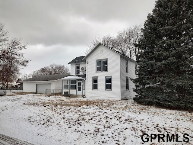 snow covered back of property with a garage