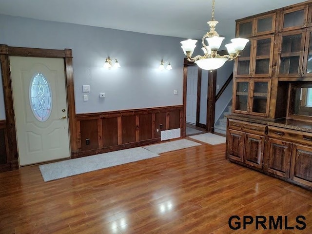 unfurnished dining area featuring a chandelier, light hardwood / wood-style flooring, and wooden walls