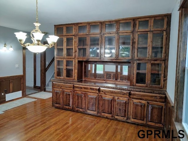 interior space with wooden walls, pendant lighting, a chandelier, and light hardwood / wood-style flooring