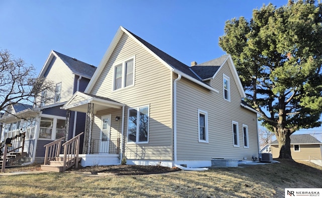 view of side of property featuring a lawn, central air condition unit, and a sunroom