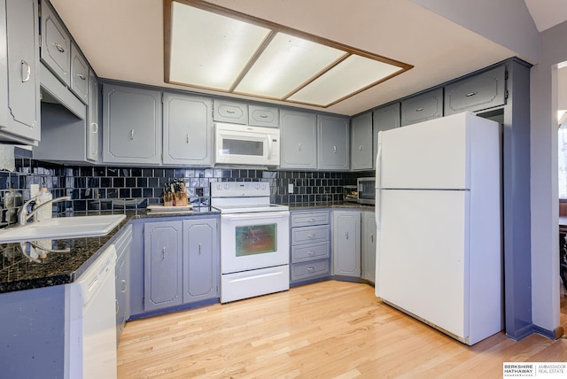 kitchen featuring light wood-type flooring, decorative backsplash, white appliances, and sink