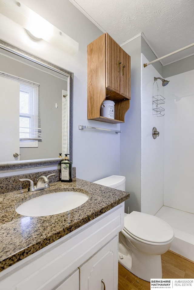 bathroom with walk in shower, vanity, a textured ceiling, hardwood / wood-style flooring, and toilet