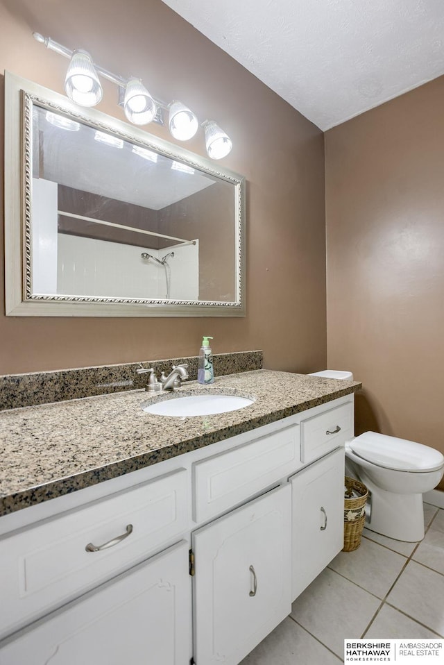 bathroom with tile patterned flooring, vanity, toilet, and walk in shower