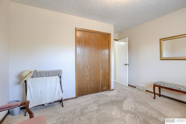 carpeted bedroom with a textured ceiling and a closet