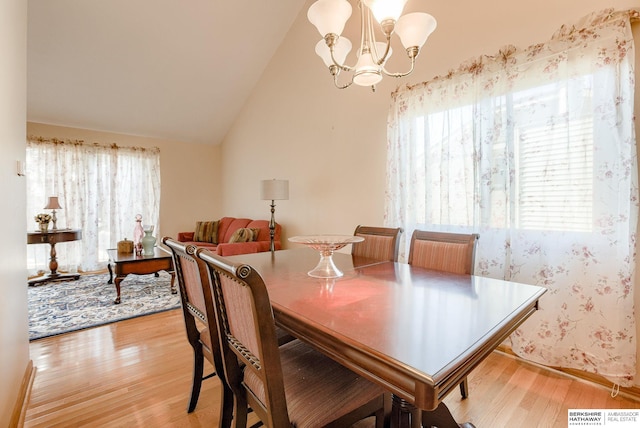 dining area with lofted ceiling, light wood-type flooring, and a chandelier