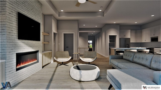 living room featuring ceiling fan, built in shelves, light hardwood / wood-style flooring, and a fireplace