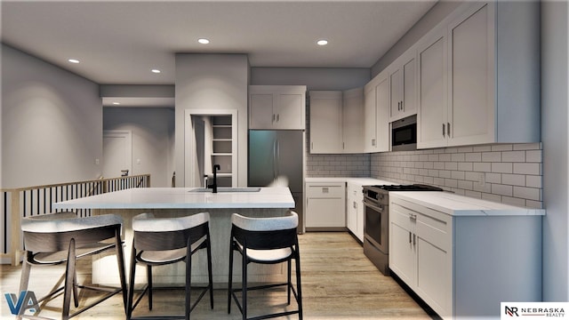 kitchen featuring white cabinetry, stainless steel appliances, decorative backsplash, sink, and a center island with sink