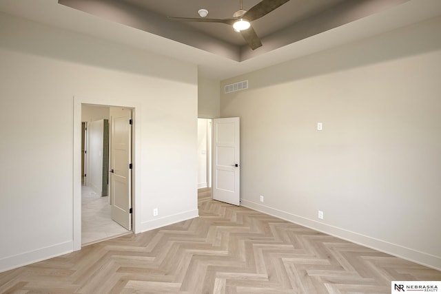 unfurnished bedroom with ceiling fan and a tray ceiling