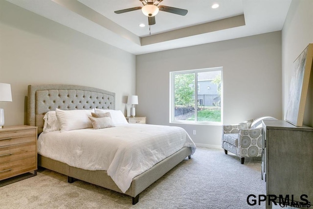 carpeted bedroom featuring ceiling fan and a tray ceiling