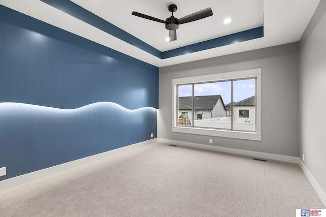 unfurnished room with ceiling fan, a tray ceiling, and carpet floors