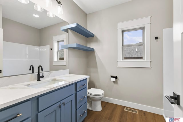 bathroom with a healthy amount of sunlight, toilet, hardwood / wood-style floors, and vanity