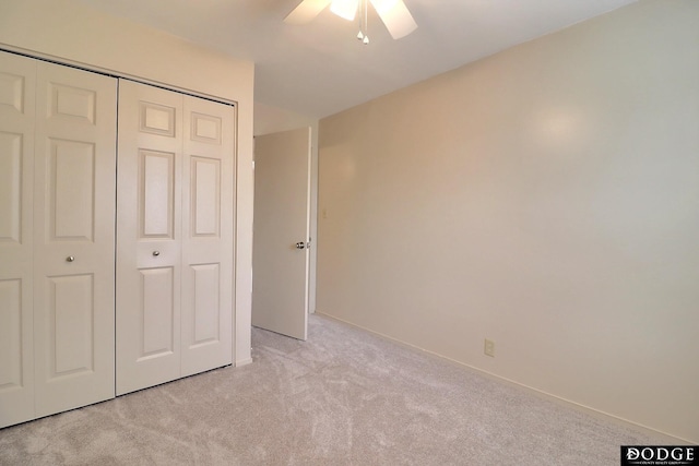 unfurnished bedroom with ceiling fan, a closet, and light carpet