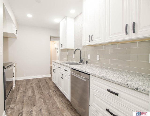 kitchen with appliances with stainless steel finishes, light wood-type flooring, white cabinetry, and sink