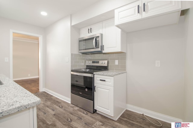 kitchen with backsplash, white cabinets, light hardwood / wood-style flooring, appliances with stainless steel finishes, and light stone counters