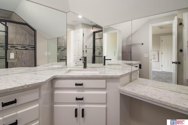 bathroom with vanity, lofted ceiling, and a textured ceiling