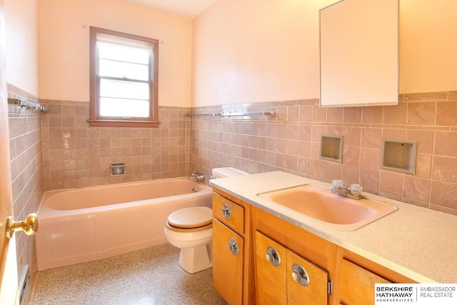 bathroom with vanity, toilet, tile walls, and a tub