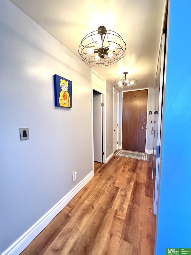 hall with hardwood / wood-style floors and an inviting chandelier