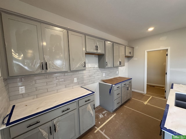 kitchen featuring tasteful backsplash, butcher block countertops, gray cabinetry, and sink