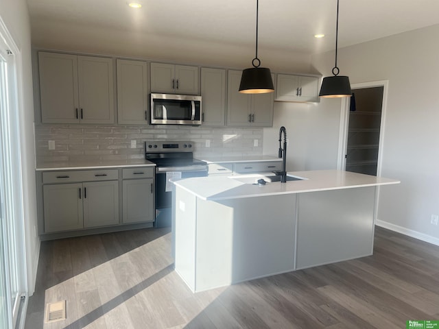 kitchen featuring sink, hanging light fixtures, a kitchen island with sink, gray cabinetry, and appliances with stainless steel finishes