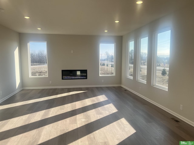 unfurnished living room featuring dark wood-type flooring and plenty of natural light