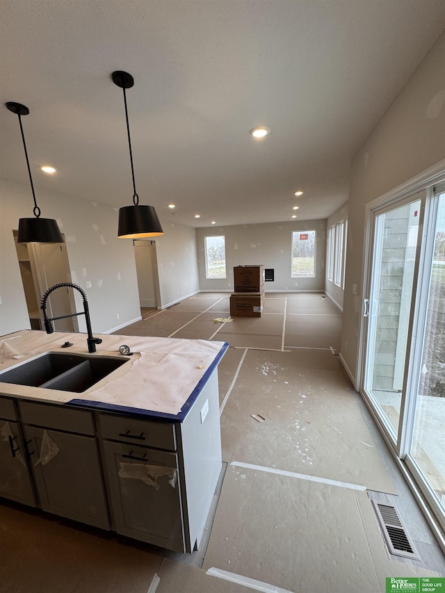 kitchen with sink, a kitchen island, a healthy amount of sunlight, and hanging light fixtures