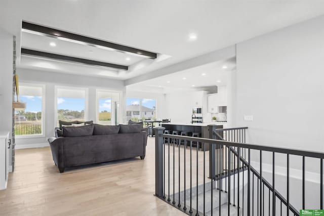 living room featuring beam ceiling and light wood-type flooring