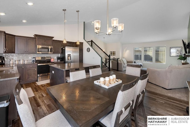 dining area featuring dark hardwood / wood-style flooring, lofted ceiling, and an inviting chandelier