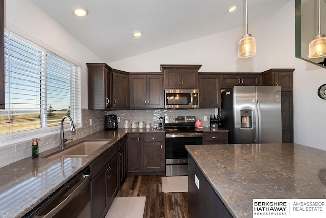 kitchen with sink, tasteful backsplash, dark stone counters, pendant lighting, and appliances with stainless steel finishes